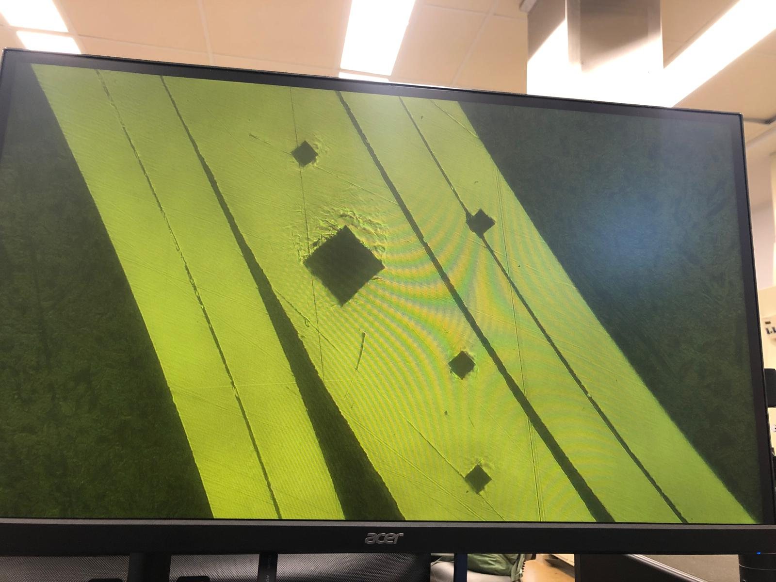 Monitor showing a microscope view of the polished tab cross-section with a row of diamond-shaped Vickers indents