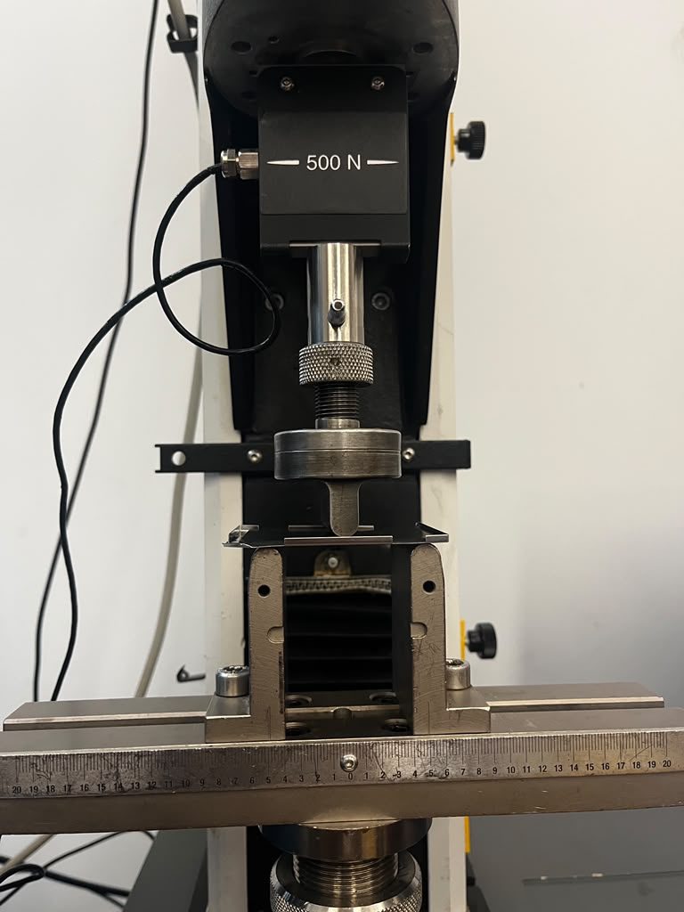 Instron testing machine with a 500 N load cell and the battery cover in a three-point bending fixture before the test
